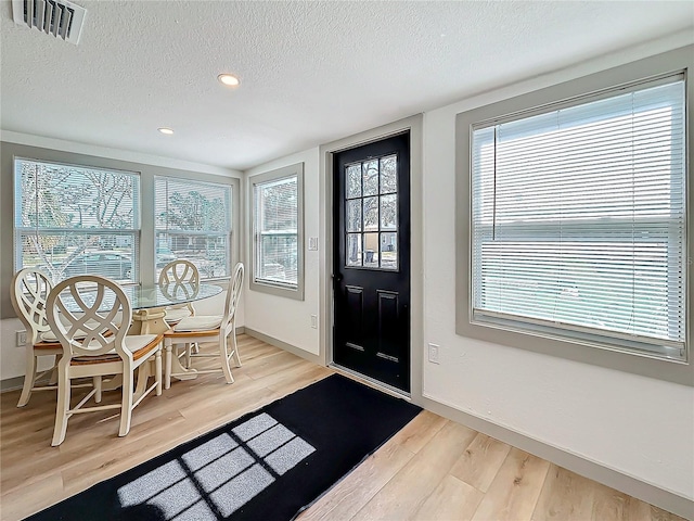 foyer featuring a healthy amount of sunlight, light hardwood / wood-style flooring, and a textured ceiling