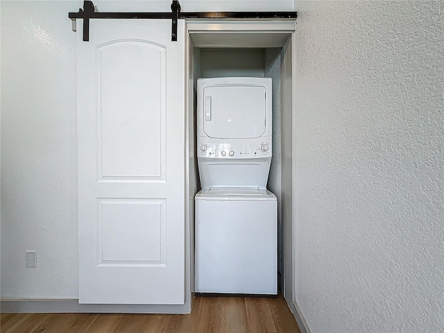 laundry area featuring stacked washer and dryer and hardwood / wood-style floors