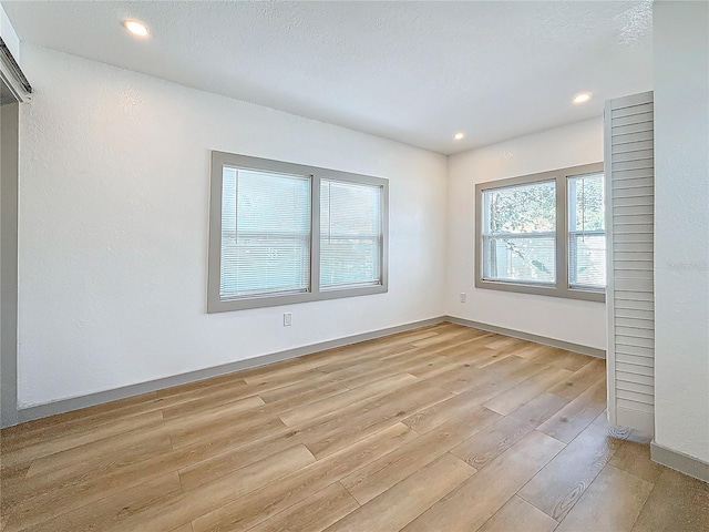 spare room featuring a textured ceiling and light wood-type flooring