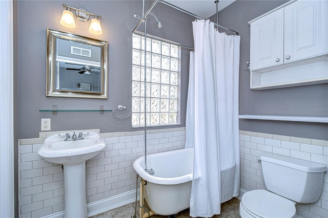 bathroom featuring a healthy amount of sunlight, toilet, and tile walls