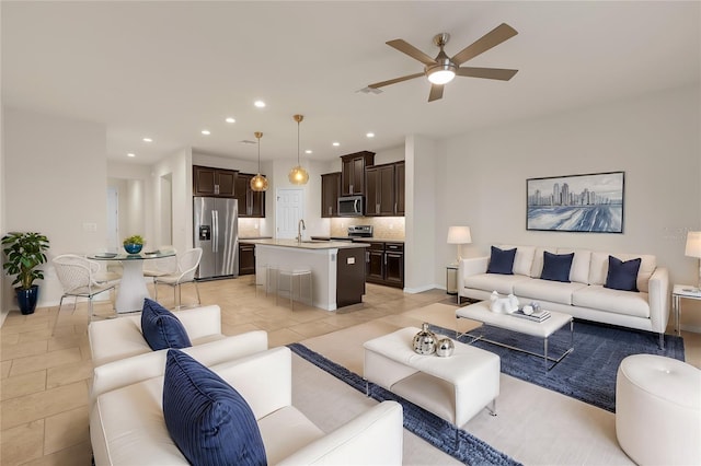 living room featuring ceiling fan, sink, and light tile patterned floors