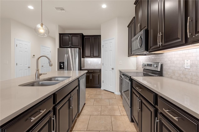 kitchen featuring sink, light tile patterned floors, backsplash, stainless steel appliances, and decorative light fixtures