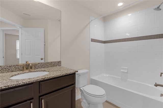 full bathroom with tiled shower / bath, vanity, and toilet