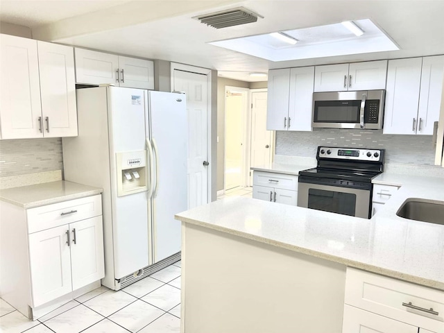 kitchen with backsplash, appliances with stainless steel finishes, light stone countertops, and white cabinets