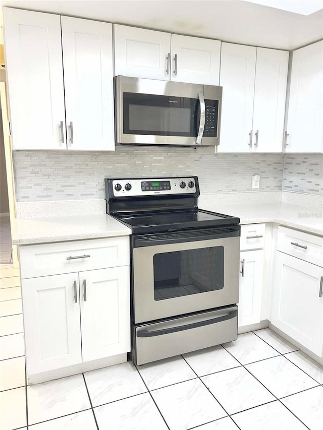 kitchen featuring stainless steel appliances, white cabinetry, and decorative backsplash