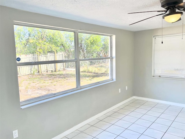 tiled empty room featuring ceiling fan and a textured ceiling