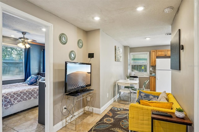 living room featuring ceiling fan and a textured ceiling