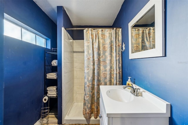 bathroom with walk in shower, vanity, and a textured ceiling