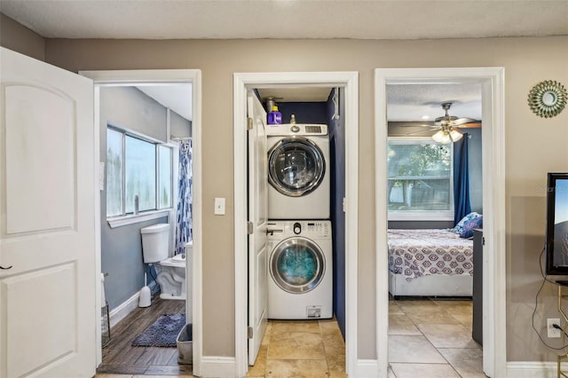 clothes washing area with ceiling fan, a textured ceiling, and stacked washing maching and dryer