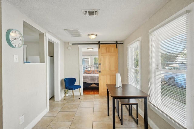 dining room featuring light tile patterned floors, a barn door, and a textured ceiling