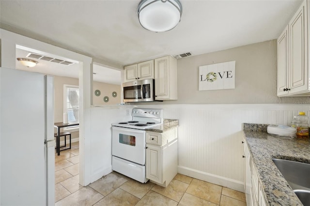 kitchen with light stone countertops, sink, light tile patterned floors, and white appliances