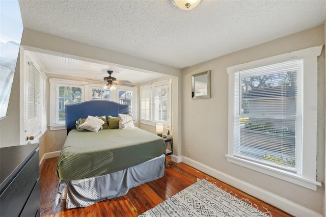 bedroom with ceiling fan, a textured ceiling, and dark hardwood / wood-style flooring