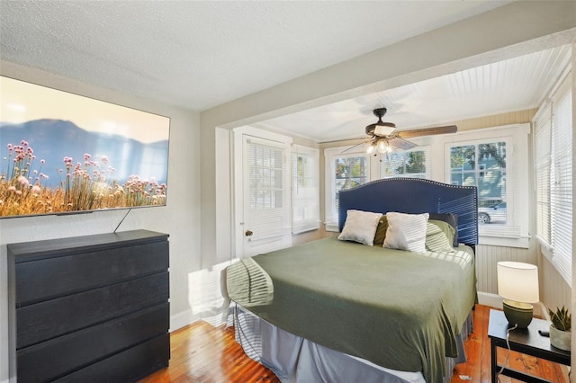 bedroom with hardwood / wood-style flooring, ceiling fan, and a textured ceiling