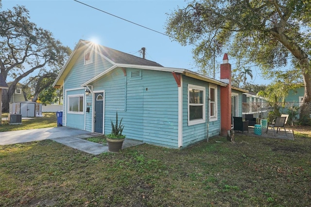 view of home's exterior with cooling unit, a patio area, a storage unit, and a lawn