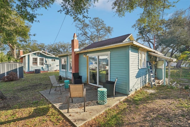 rear view of property featuring a storage unit, central AC unit, a patio area, and a lawn