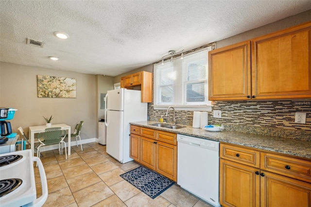 kitchen featuring sink, white appliances, light tile patterned floors, dark stone countertops, and backsplash