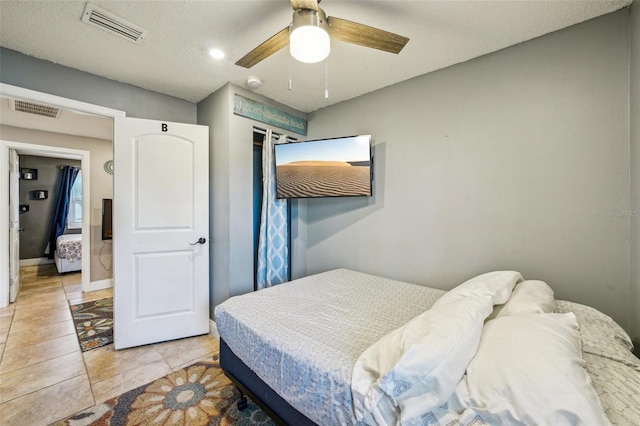 tiled bedroom with ceiling fan and a closet