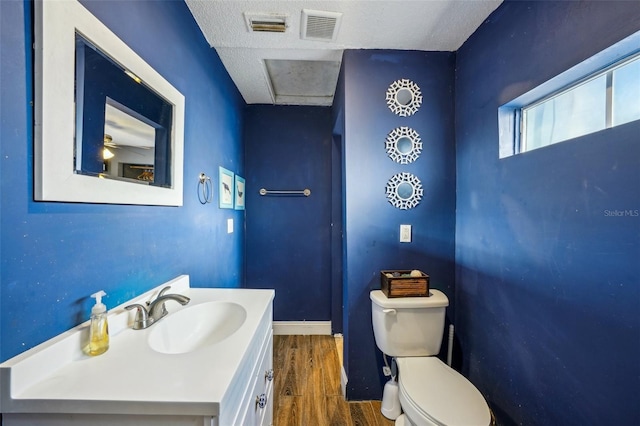 bathroom featuring vanity, toilet, hardwood / wood-style floors, and a textured ceiling