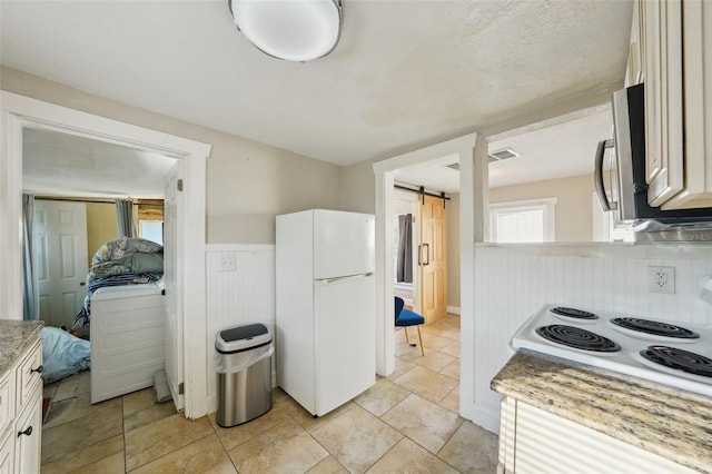 kitchen featuring white refrigerator, white cabinetry, a barn door, and cooktop