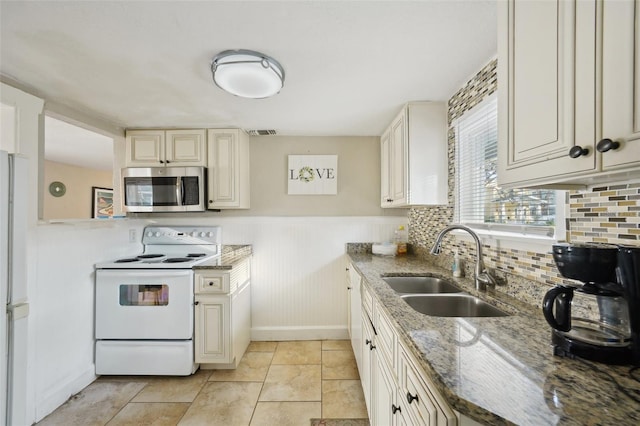 kitchen featuring sink, tasteful backsplash, light tile patterned floors, dark stone countertops, and white electric stove