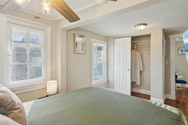 bedroom with a closet, beam ceiling, dark hardwood / wood-style floors, and a textured ceiling