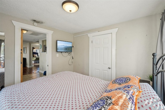 tiled bedroom with a textured ceiling and a closet