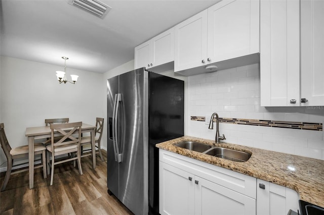 kitchen with pendant lighting, sink, white cabinetry, light stone countertops, and stainless steel fridge with ice dispenser