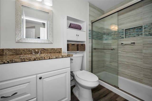 bathroom featuring vanity, wood-type flooring, a shower with shower door, and toilet