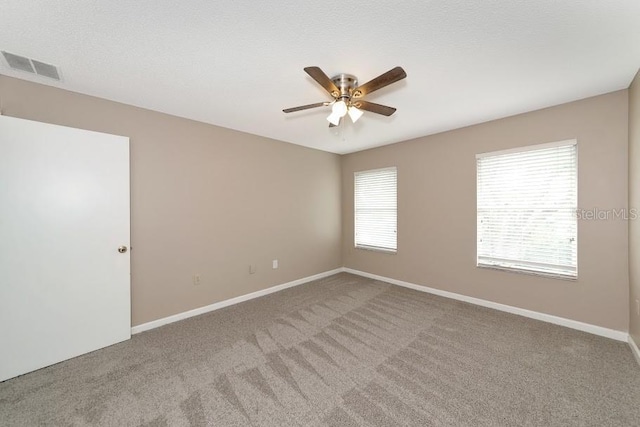 carpeted spare room featuring a textured ceiling and ceiling fan