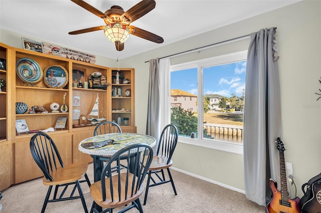 dining space featuring light carpet and ceiling fan