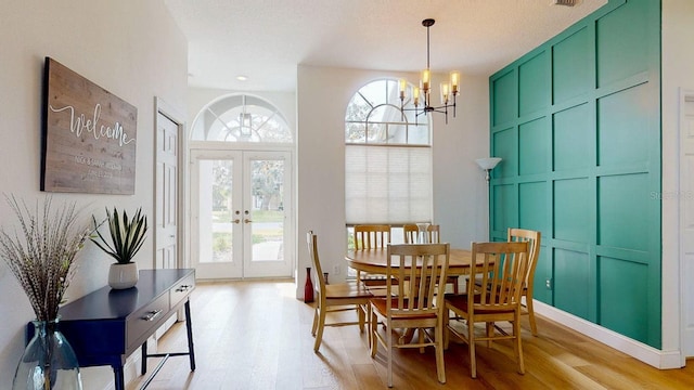 dining space featuring light hardwood / wood-style floors, french doors, and a chandelier