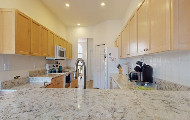 kitchen with tasteful backsplash, white appliances, light stone countertops, and light brown cabinets