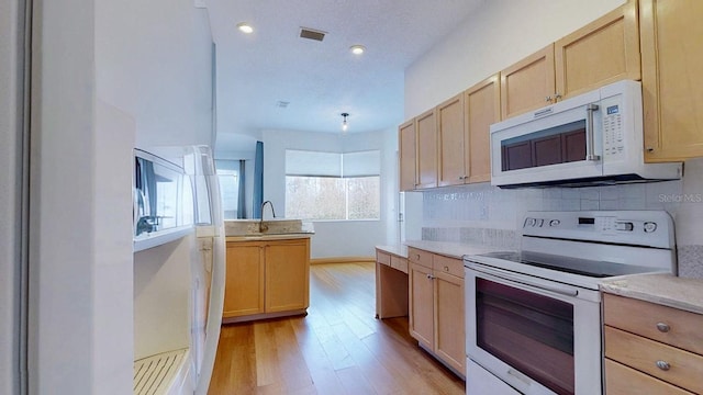 kitchen featuring light brown cabinetry, white appliances, and decorative backsplash