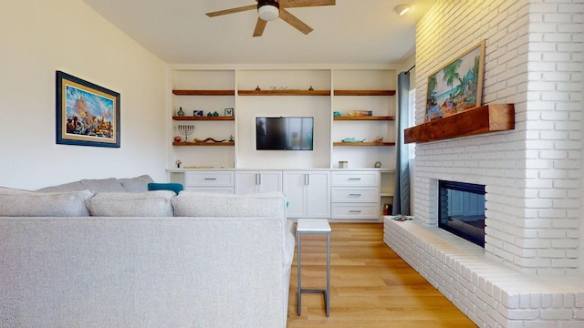 living room featuring a fireplace, light hardwood / wood-style flooring, built in features, and ceiling fan