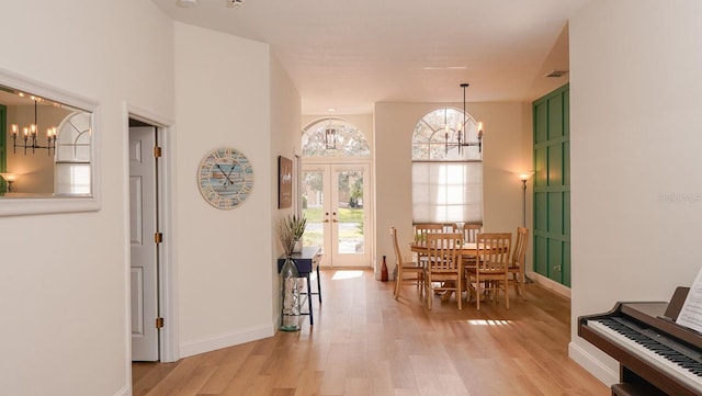 dining area with a notable chandelier, light hardwood / wood-style flooring, and french doors