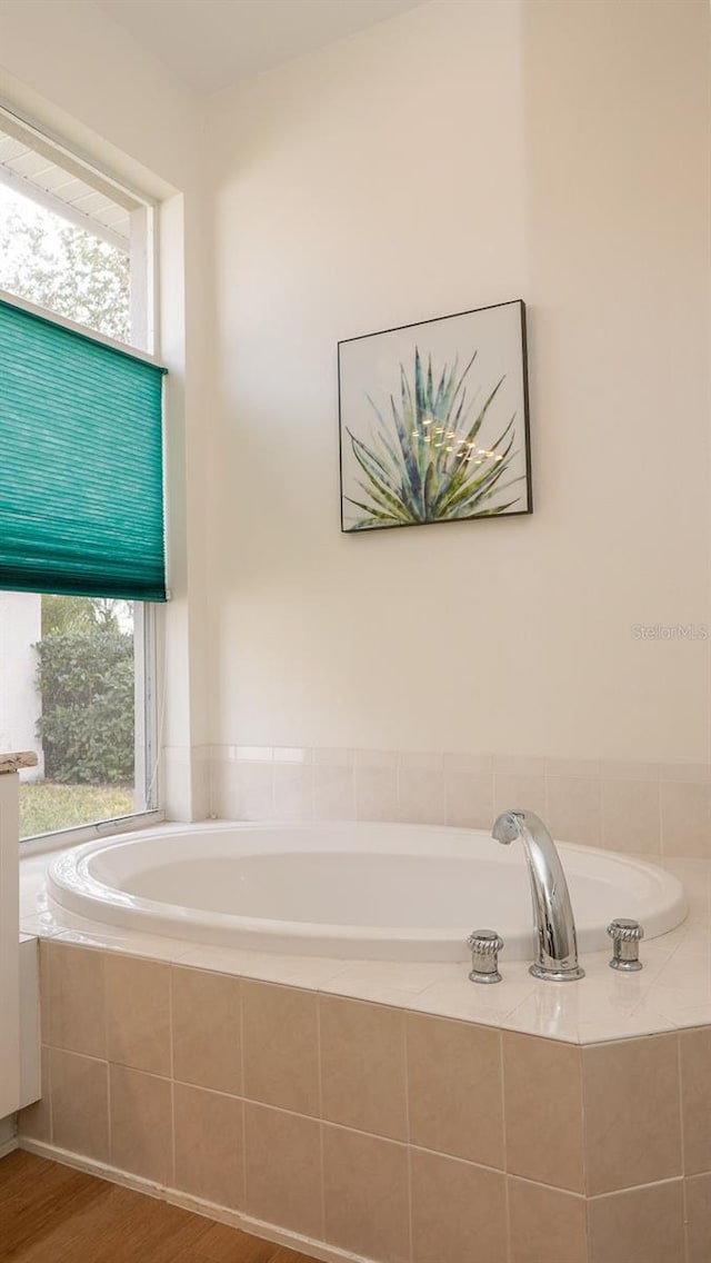 bathroom featuring tiled tub, plenty of natural light, and hardwood / wood-style flooring