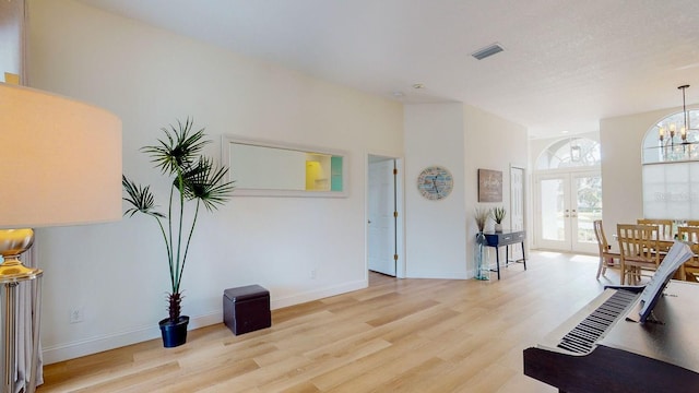 interior space featuring light hardwood / wood-style floors, french doors, and a chandelier