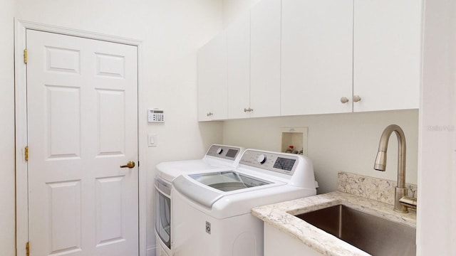 washroom featuring cabinets, washing machine and dryer, and sink