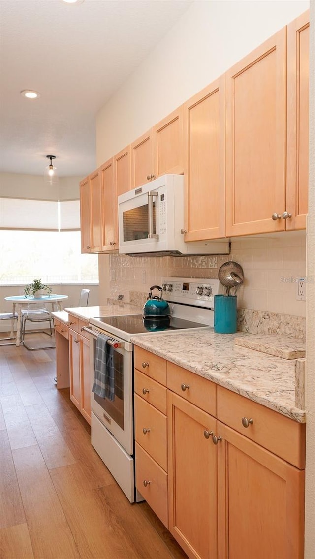 kitchen with white appliances, light hardwood / wood-style flooring, decorative backsplash, and light brown cabinets