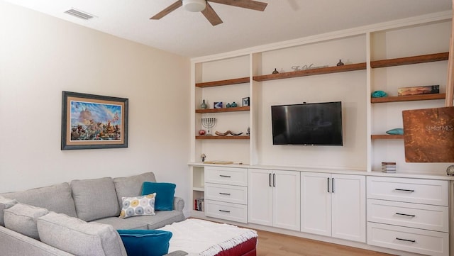 living room with built in shelves, light hardwood / wood-style floors, and ceiling fan