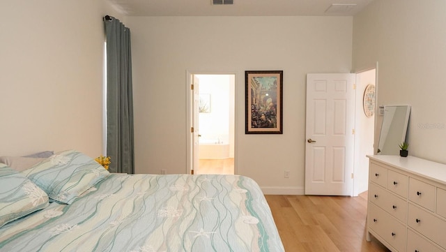 bedroom with ensuite bathroom and light wood-type flooring