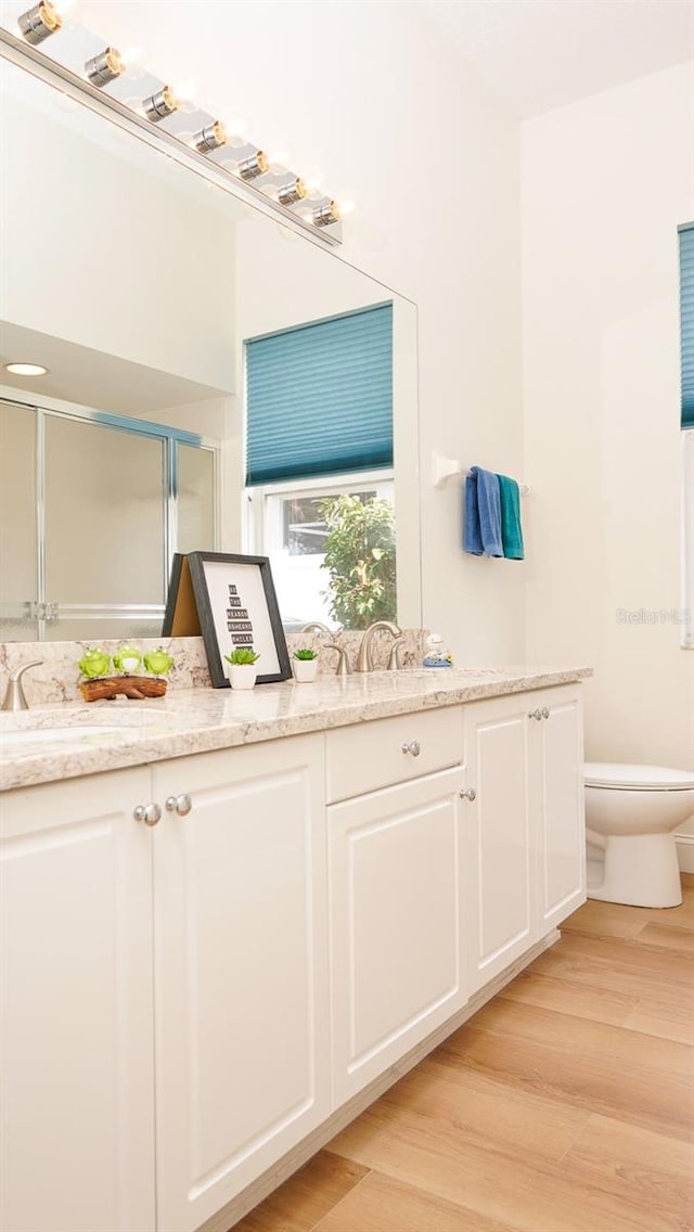 bathroom featuring vanity, hardwood / wood-style floors, an enclosed shower, and toilet