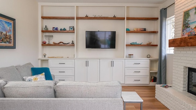 living room with built in features, a fireplace, and light hardwood / wood-style floors