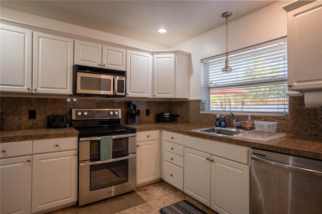 kitchen featuring appliances with stainless steel finishes, decorative light fixtures, white cabinetry, sink, and backsplash