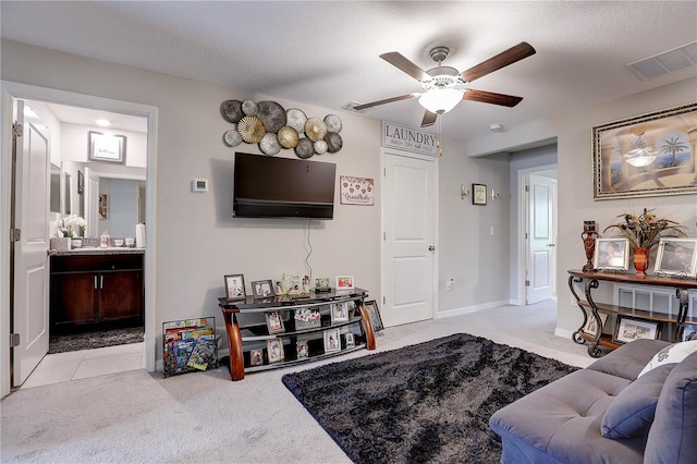 living room featuring ceiling fan, light carpet, and a textured ceiling