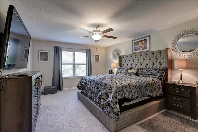 bedroom featuring ceiling fan, light colored carpet, and a textured ceiling