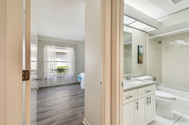 full bathroom with hardwood / wood-style flooring, vanity, a textured ceiling, toilet, and tiled shower / bath