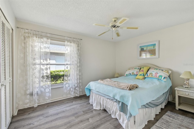 bedroom with ceiling fan, hardwood / wood-style flooring, a closet, and a textured ceiling