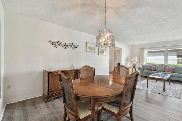 dining room with wood-type flooring, a textured ceiling, and a chandelier