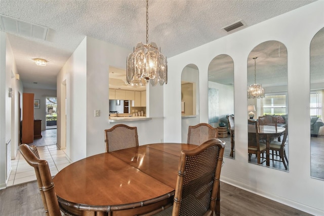 dining room featuring hardwood / wood-style flooring, a textured ceiling, and a chandelier